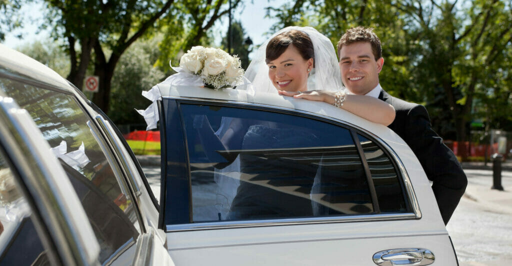 a bride and groom getting out of a car.